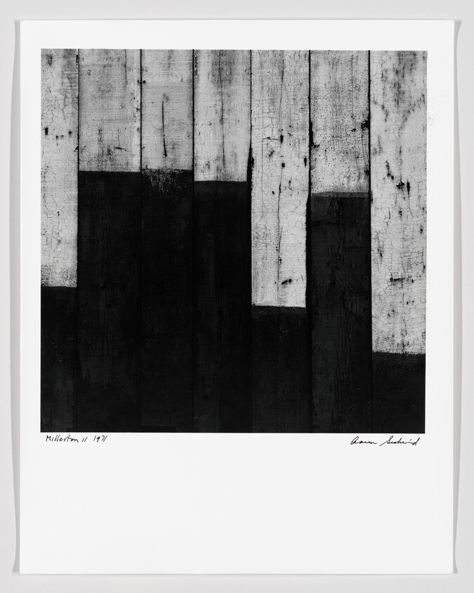Monochrome abstract artwork with vertical black and white distressed patterns, signed at the bottom.