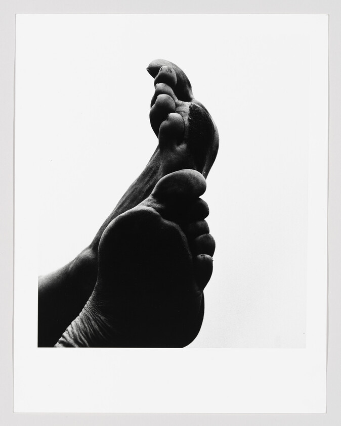 Two bare feet soles shown in high-contrast black-and-white with toes curled upward.