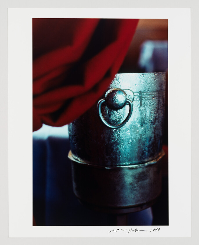 A close-up of a weathered metal bucket with a round ring handle and a red cloth draped.