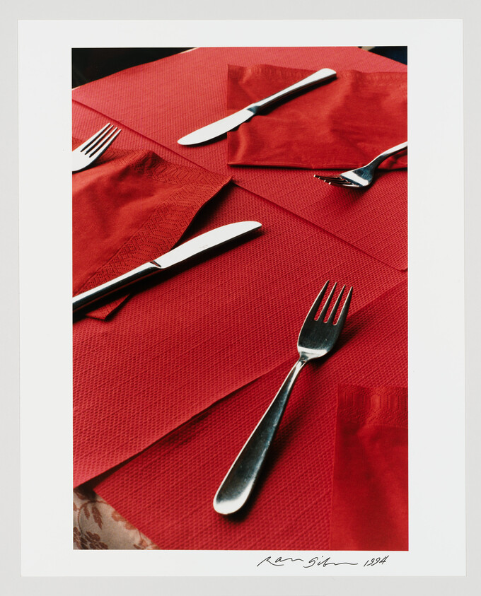 Three forks and two knives arranged on red textured napkins and tablecloth.