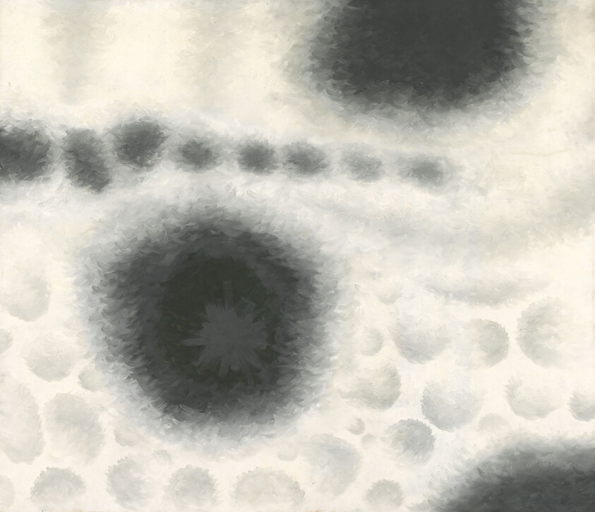 Gray and black circular blotches form a soft, watercolor-like dotted pattern on a pale background.