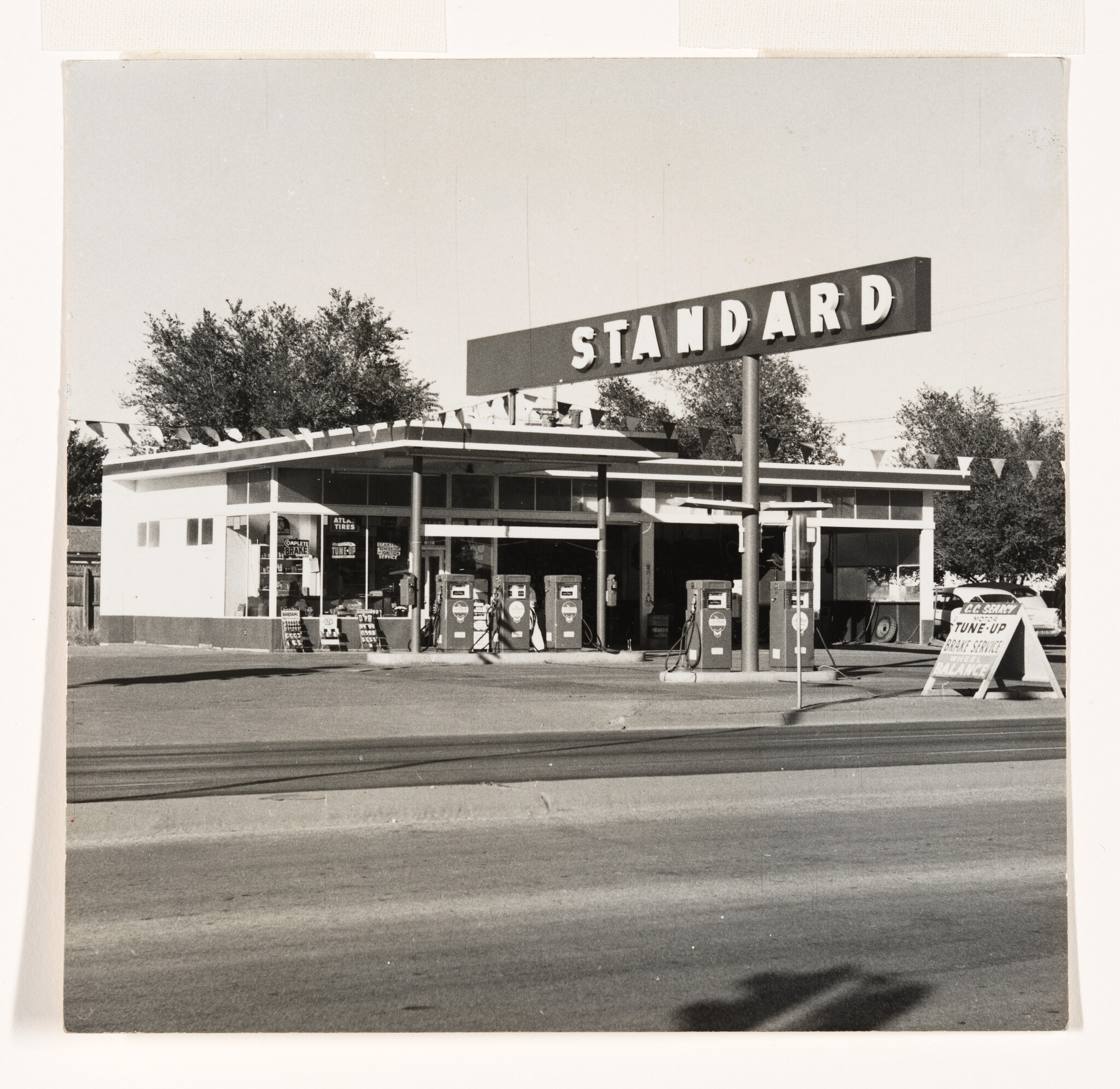 Standard gas station with vintage pumps and service sign by the roadside.