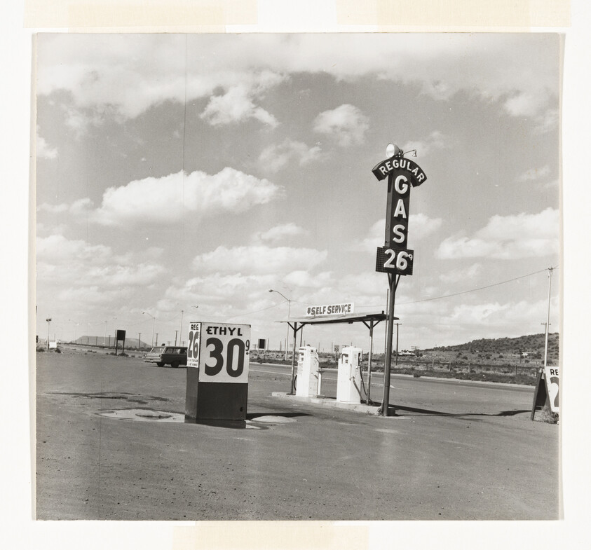 Desert gas station with tall 'Gas 26¢' sign and pump price board reading Ethyl 30¢.