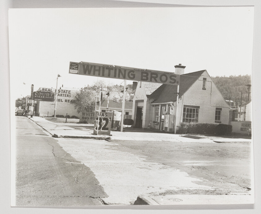 Whiting Bros gas station with canopy and price sign on a quiet street corner.