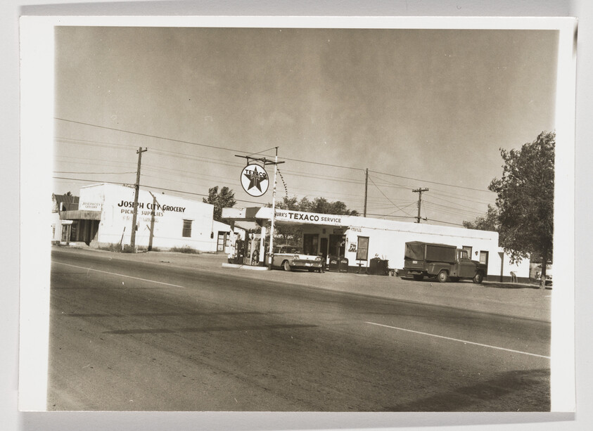Vintage Texaco service station with gas pumps, parked cars, and Joseph City Grocery building beside it.