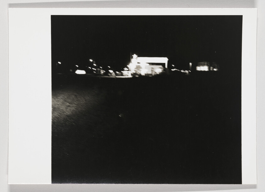 Distant lit building and streetlights on a dark night with a mostly black foreground.