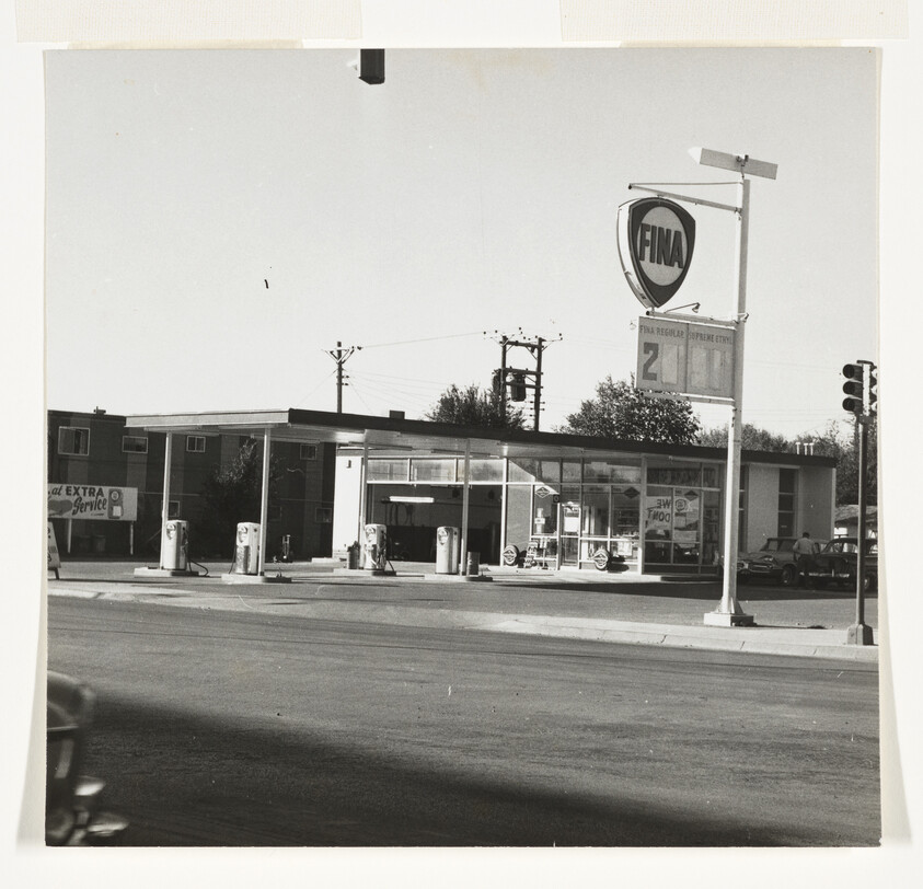 A FINA gas station with multiple vintage pumps under a canopy and a tall sign.