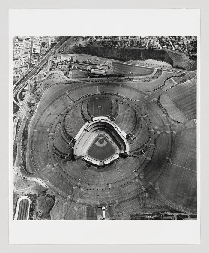 Aerial view of a baseball stadium surrounded by concentric parking lots and nearby roads.
