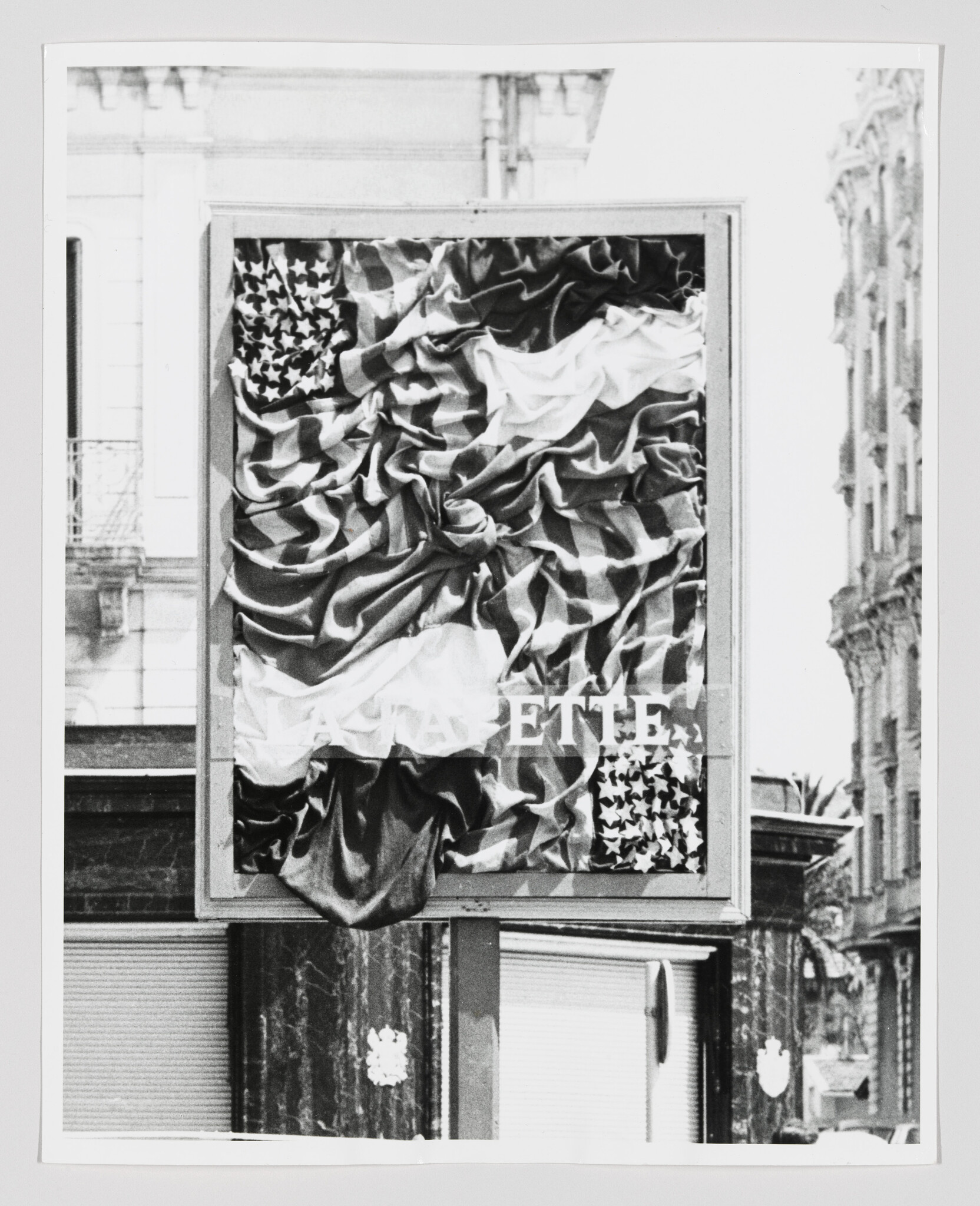 A street billboard displaying a tightly folded American flag fabric artwork with partial text visible.