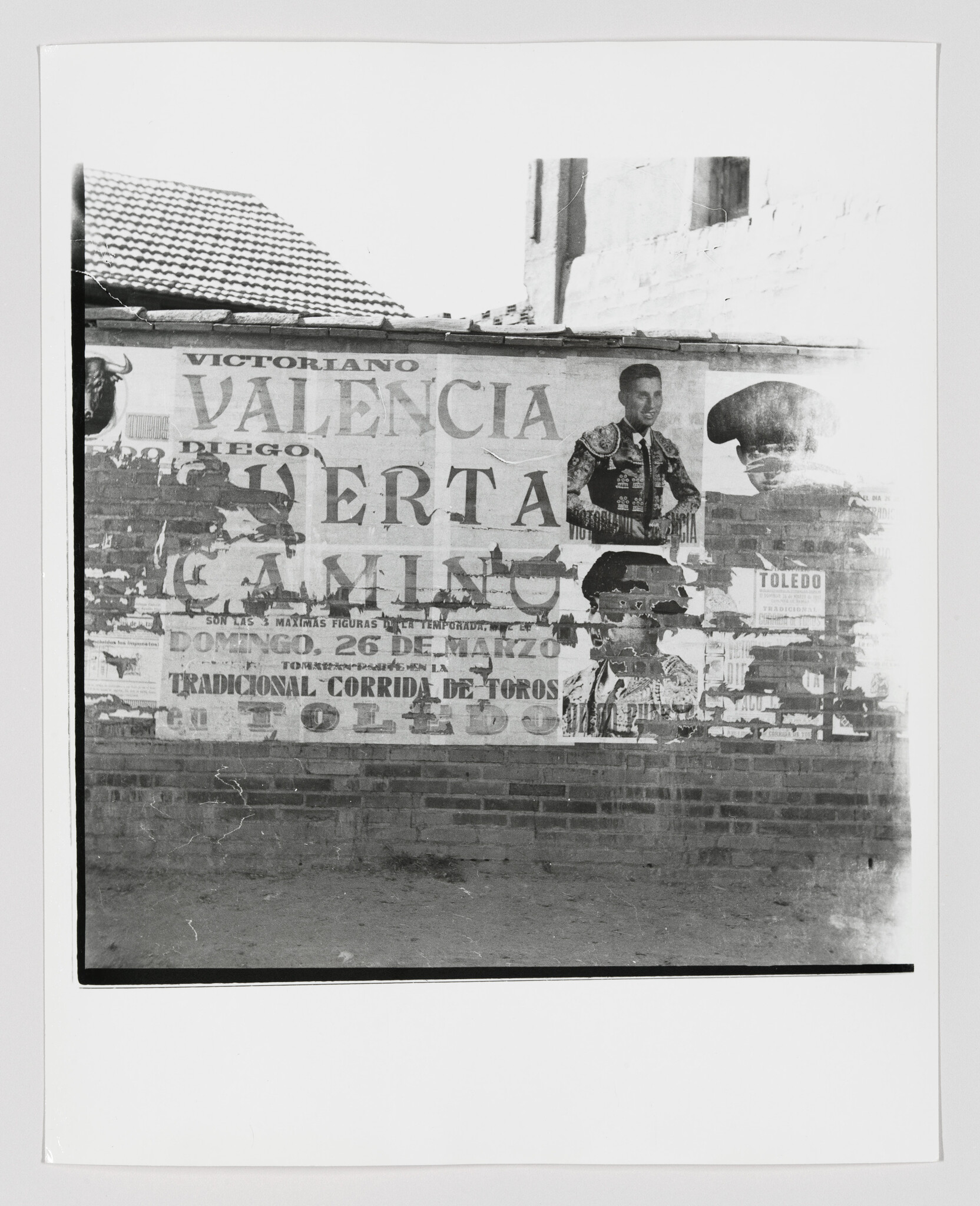 Worn poster on a brick wall advertising a Valencia bullfight with portraits of matadors.