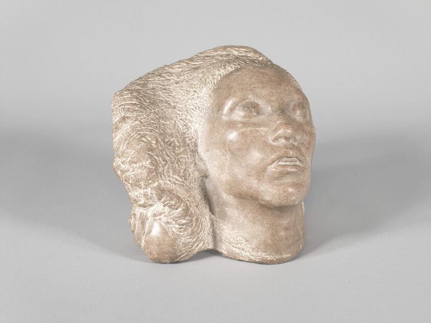 Carved stone sculpture of a human head with textured hair looking upward.