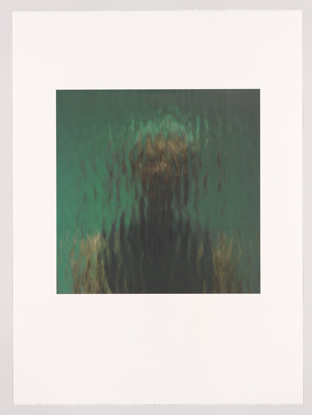 Blurred person standing behind rippled glass with green background, features obscured.