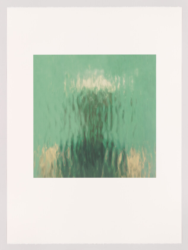 Blurry human silhouette seen through rippling green glass, creating distorted reflection.