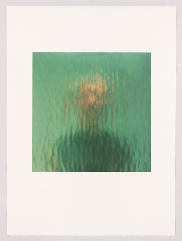 Silhouetted person blurred behind rippled green glass, head and shoulders visible.