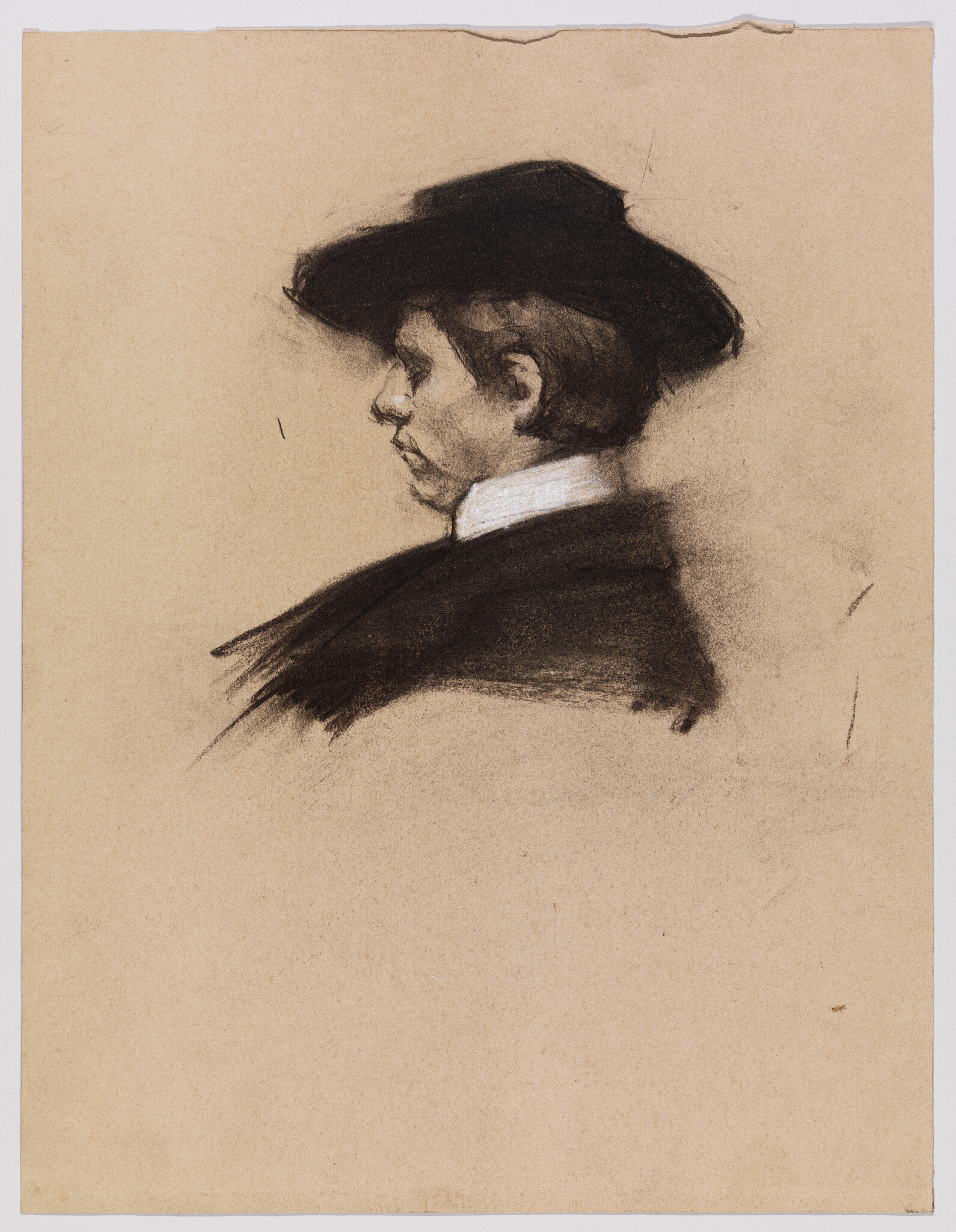 Young person in profile wearing a dark wide-brimmed hat and white collared shirt.