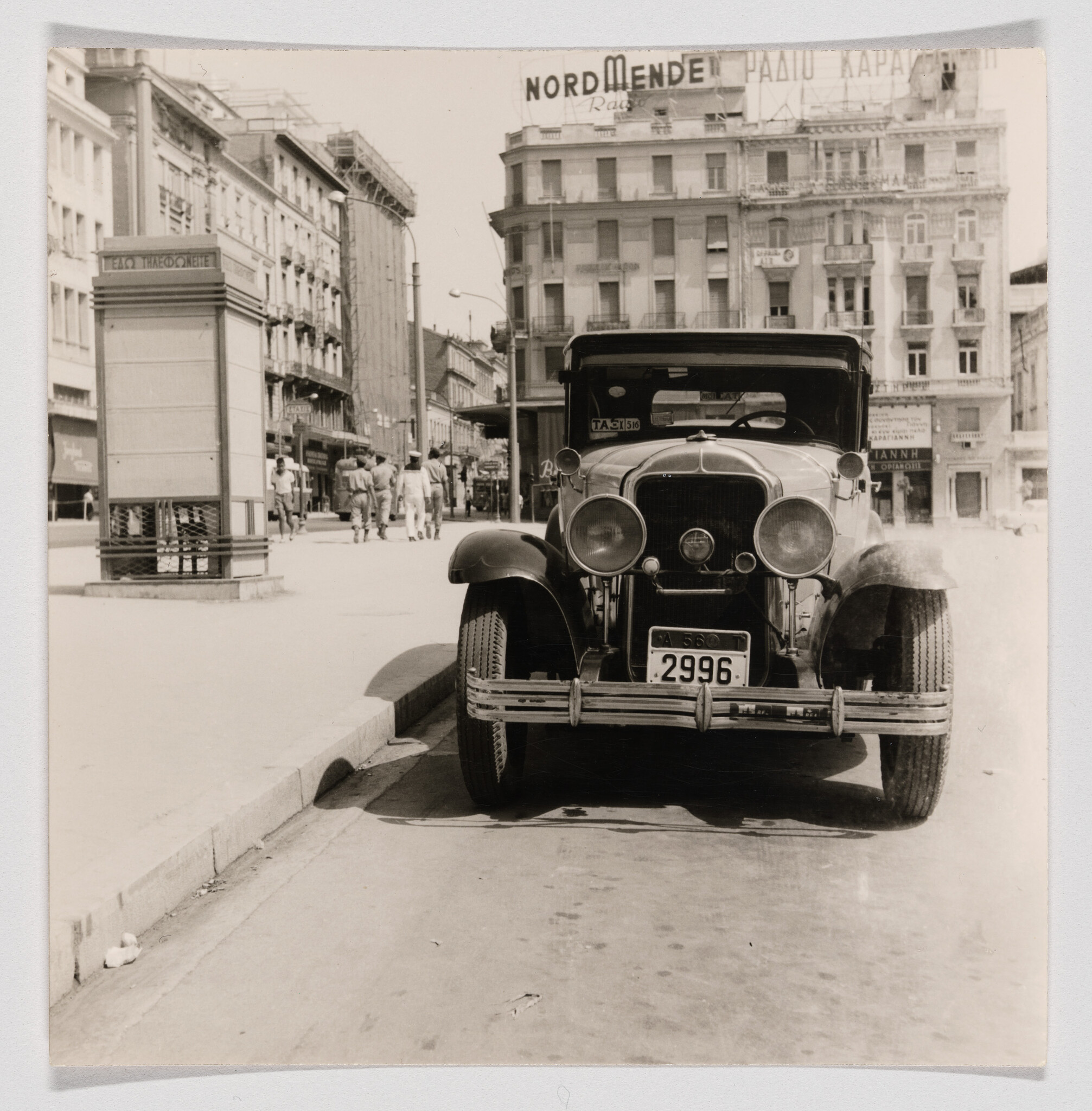 A vintage car with license plate 2996 parked on a busy city street.