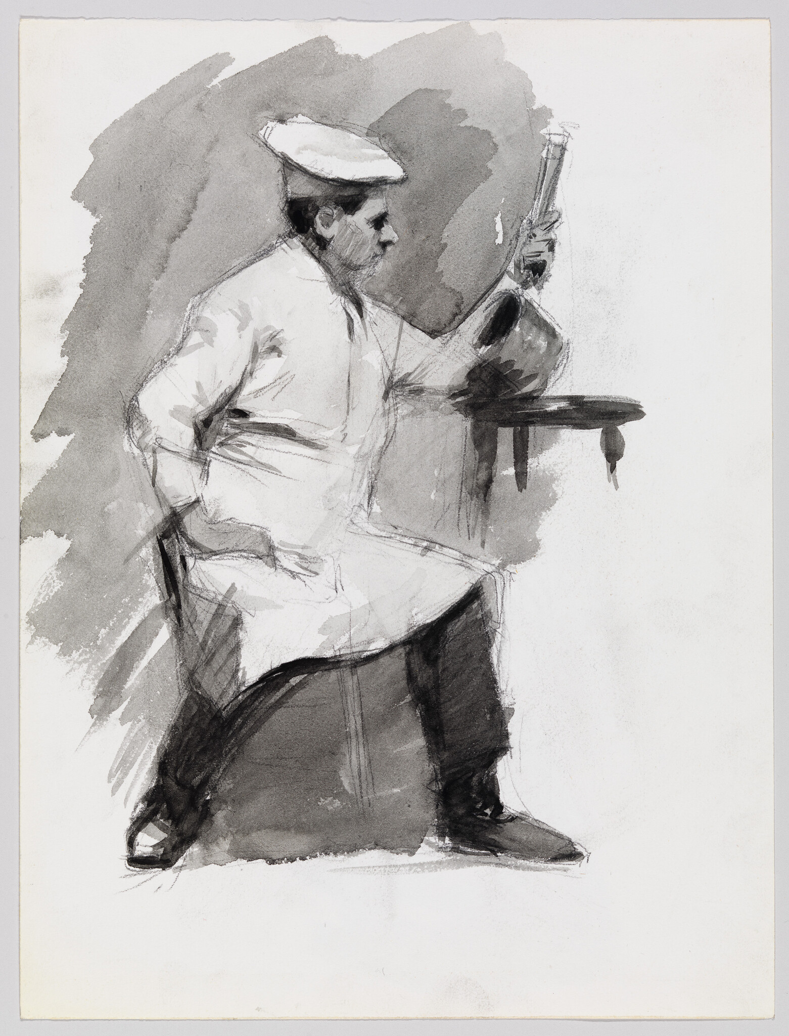 A seated man wearing a cap and coat examines a bottle on a small table.