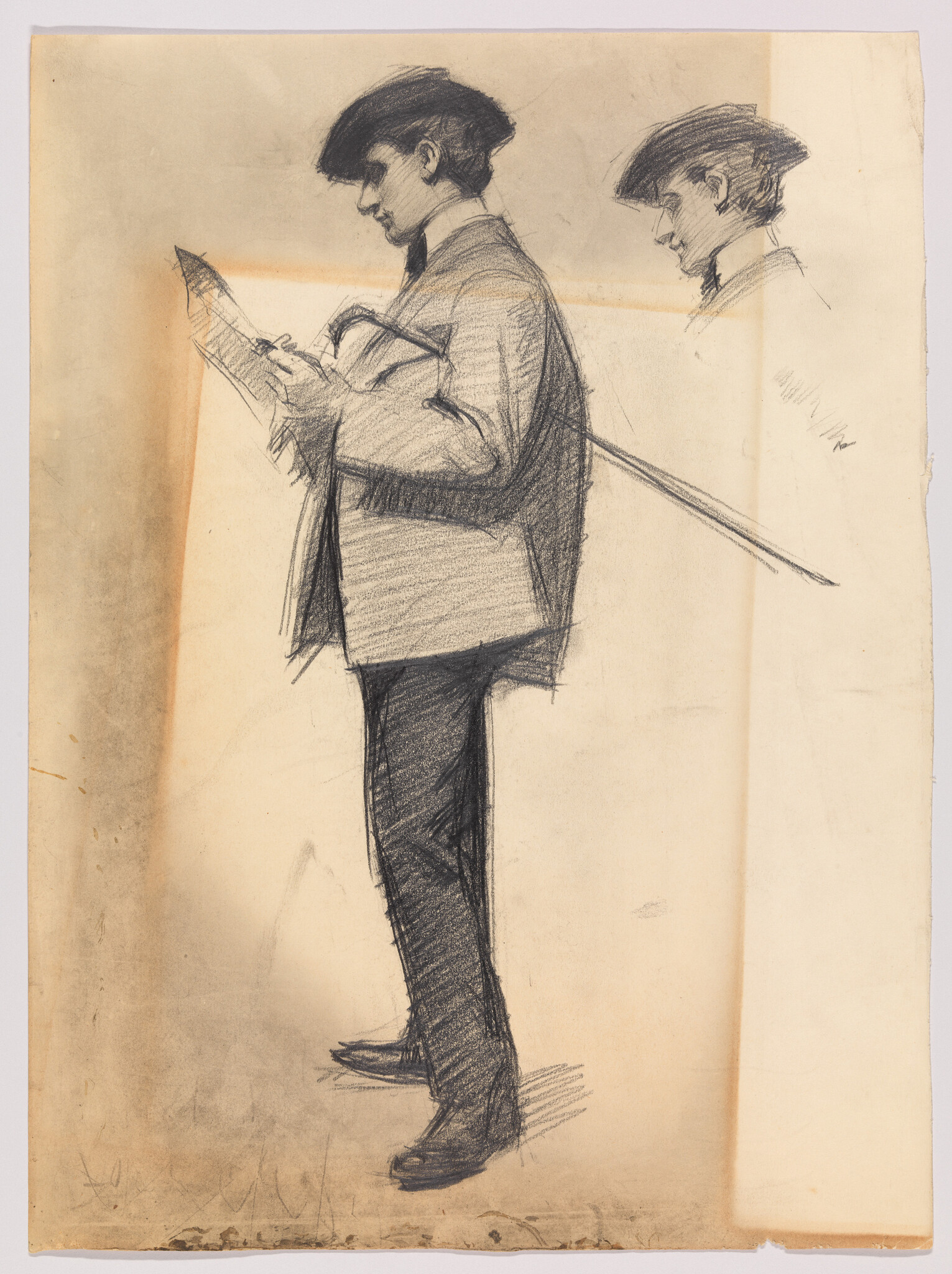 A standing young man in a hat reads a newspaper while holding a cane over his shoulder.