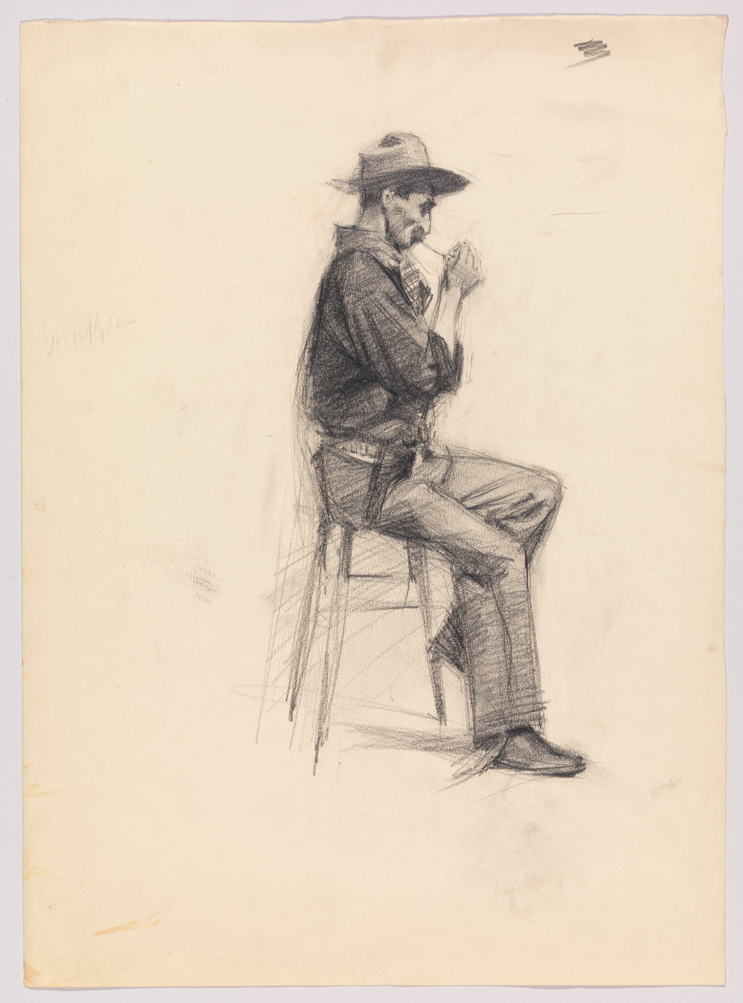 A seated man wearing a hat sits on a stool and lights a cigarette.