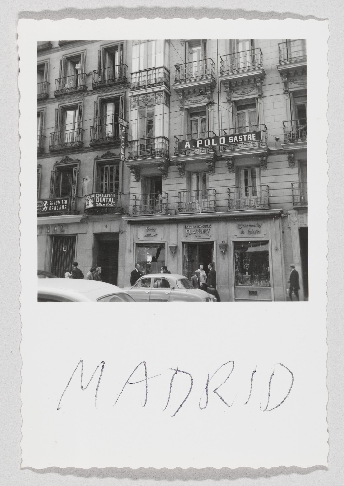 People and cars pass in front of a multi-story Madrid building with an A. Polo Sastre sign.