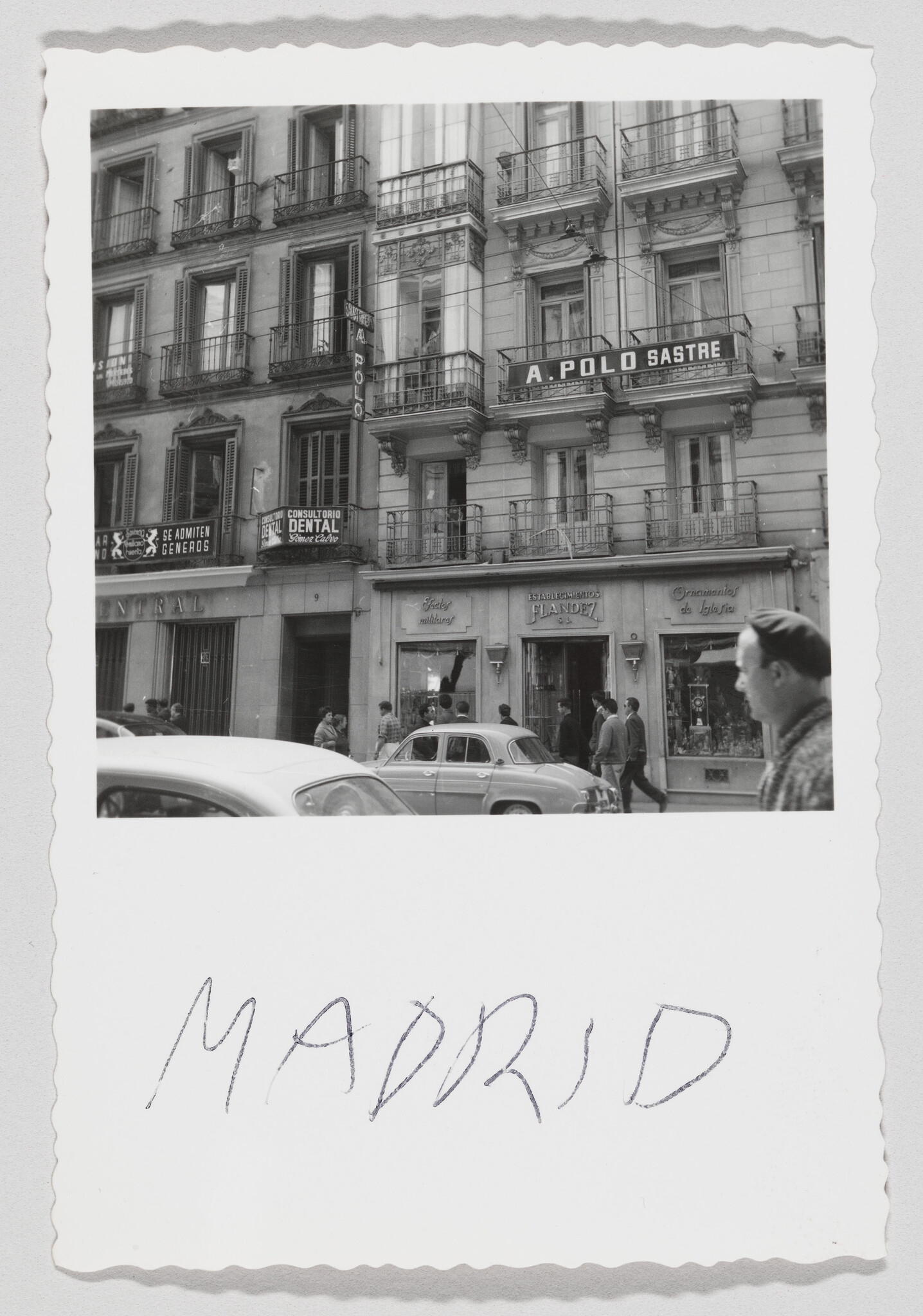 People and cars pass a Madrid storefront with balconies and an A. Polo Sastre sign.