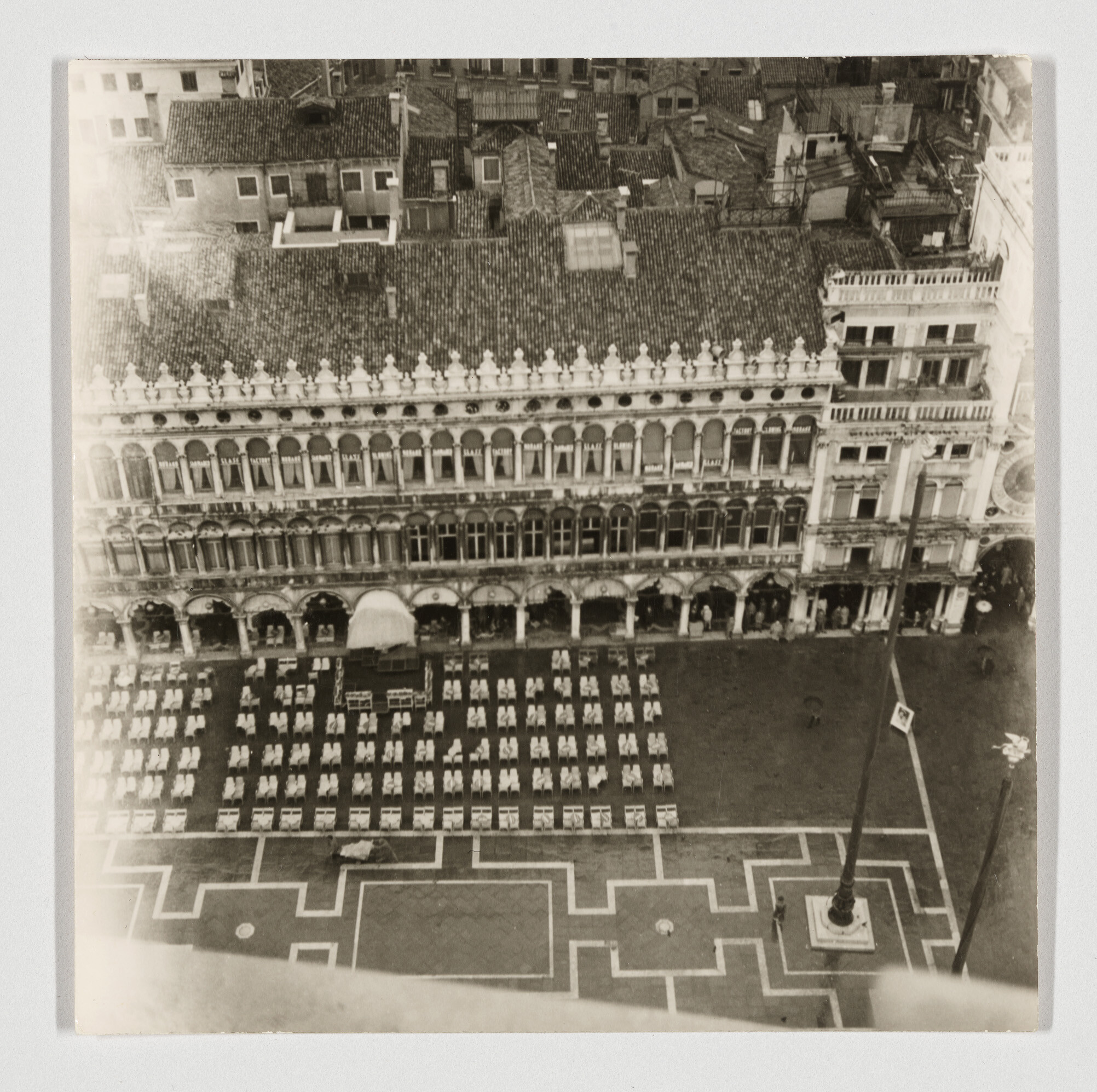 Ornate three-story building overlooks a plaza filled with neatly arranged rows of empty chairs.