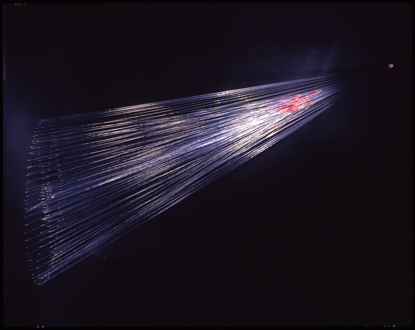 Long fiber optic strands fanning out and glowing with blue and pink light against darkness.