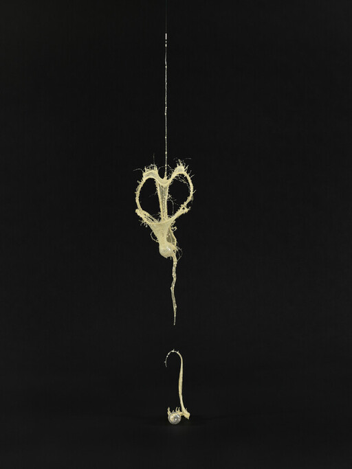 A string of pale, sticky liquid forms a heart-shaped loop and a droplet below.