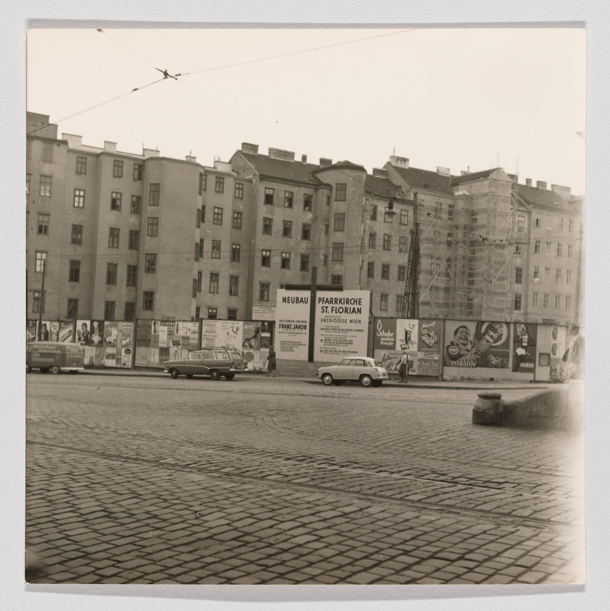 Row of old apartment buildings with construction scaffolding and advertising posters along the street.