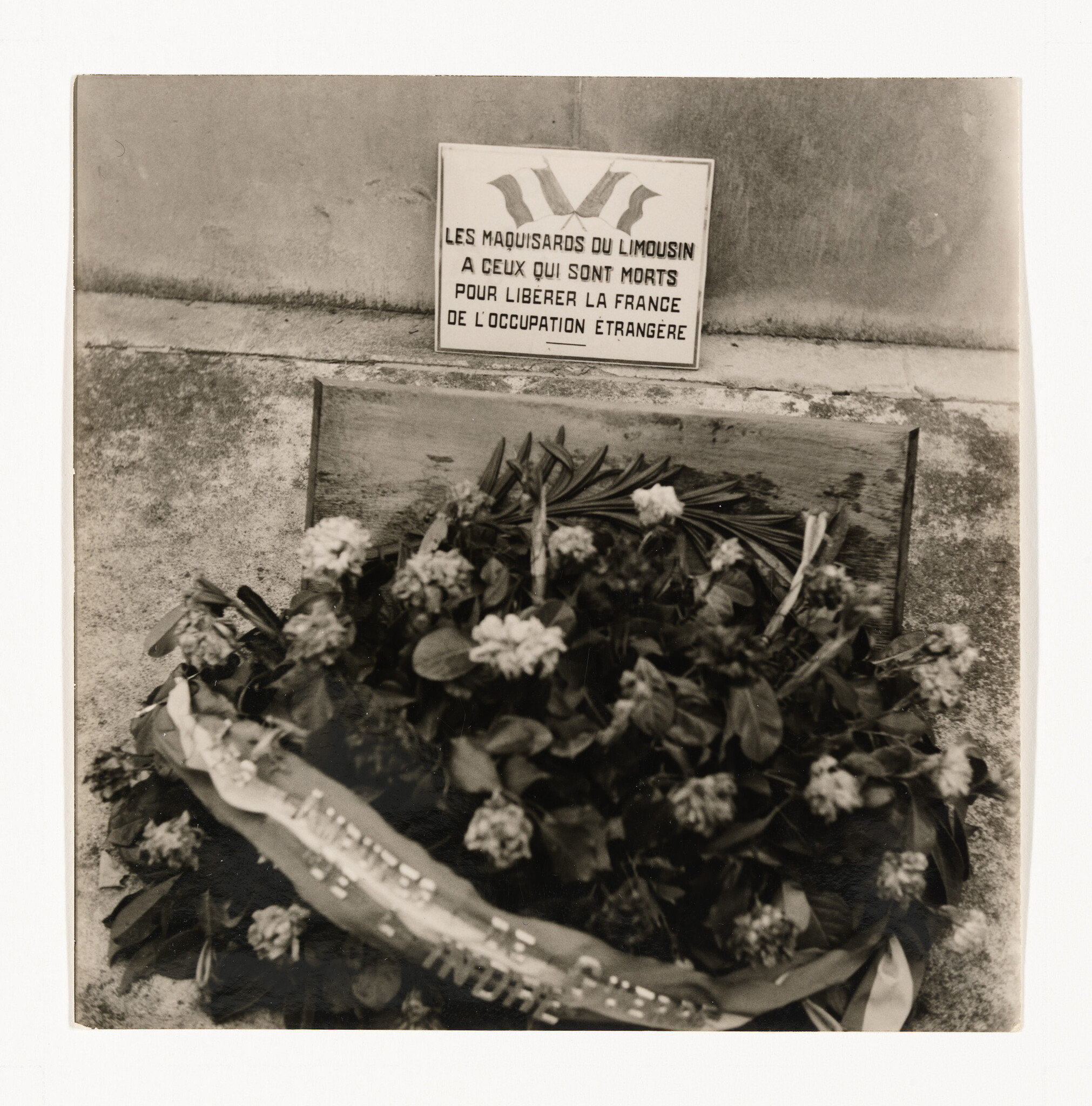 Wreath of flowers placed beneath a plaque honoring Les Maquisards du Limousin who died liberating France.
