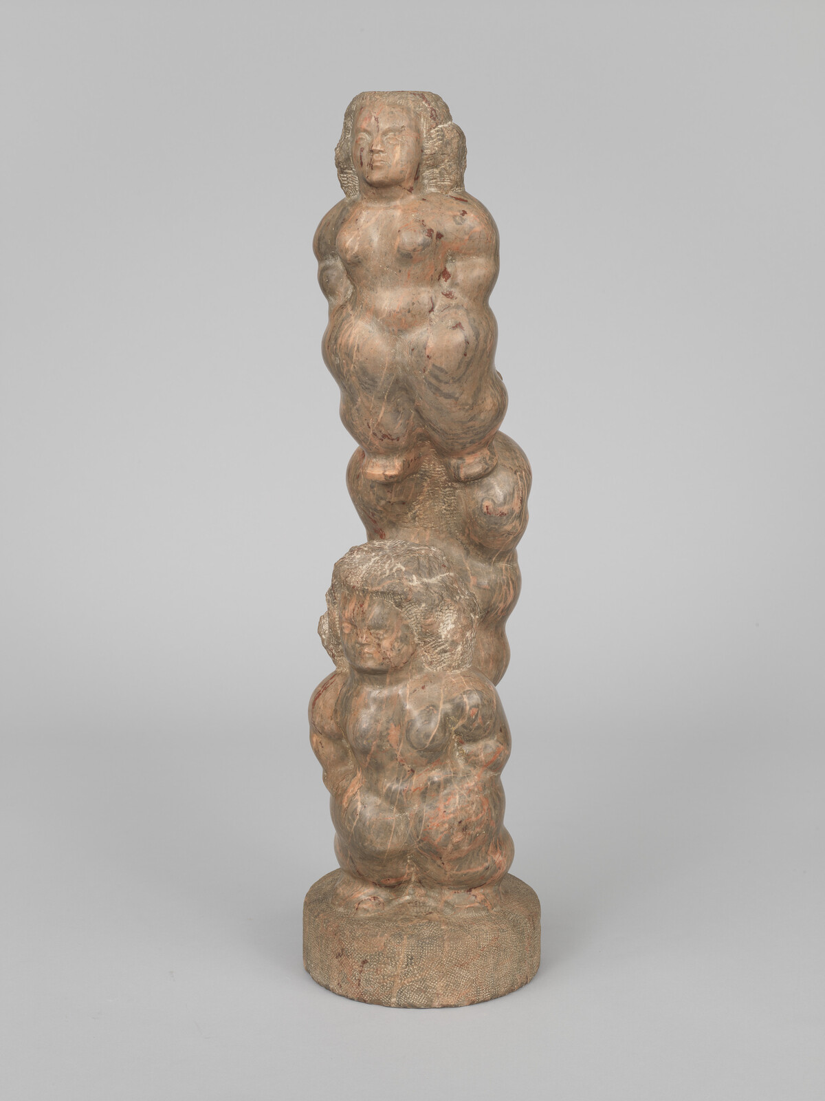 Two stacked carved figures with rounded bodies standing on a circular base.