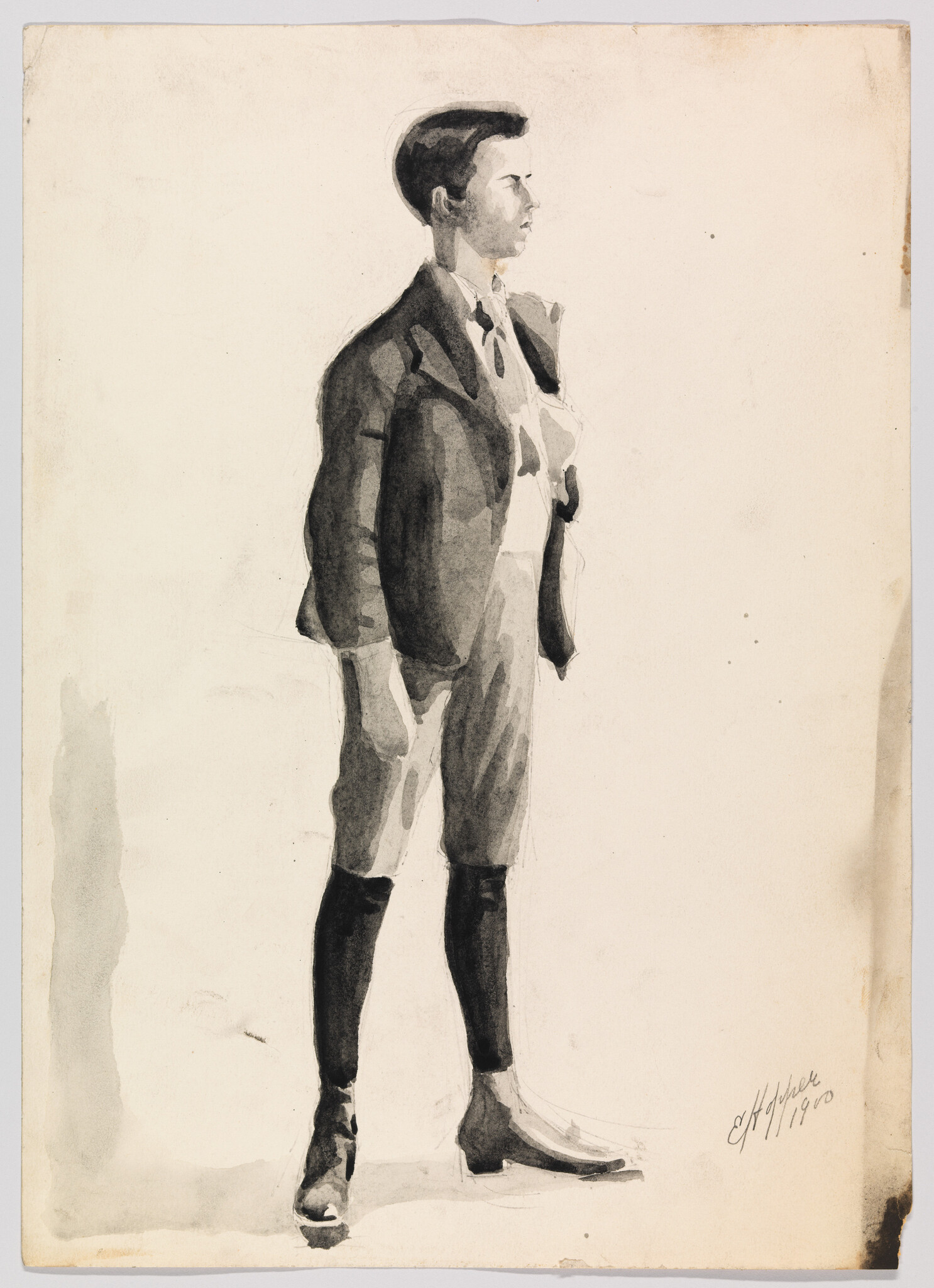 Young man standing in profile wearing a suit jacket, knickerbockers, and knee-high socks.