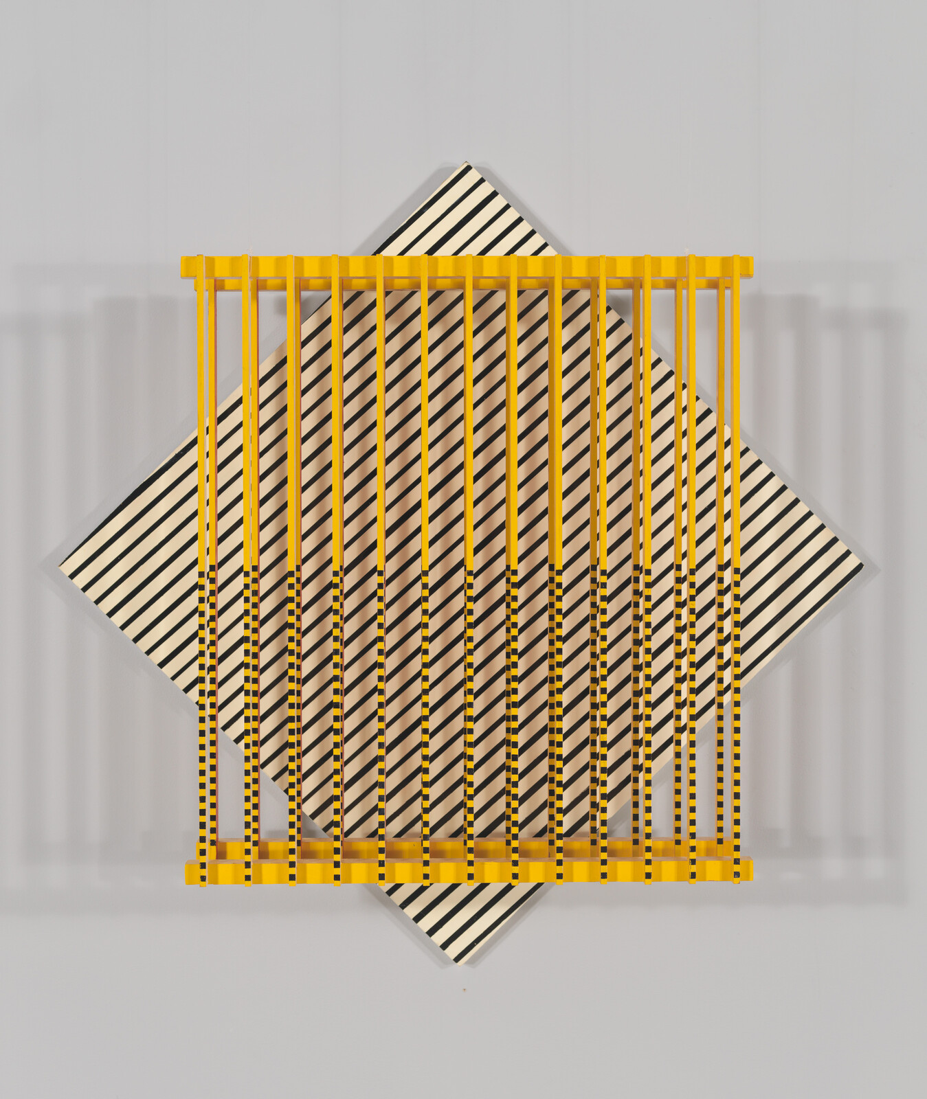 Yellow vertical bars overlay a rotated black-and-white striped square, casting soft shadows on a gray background.