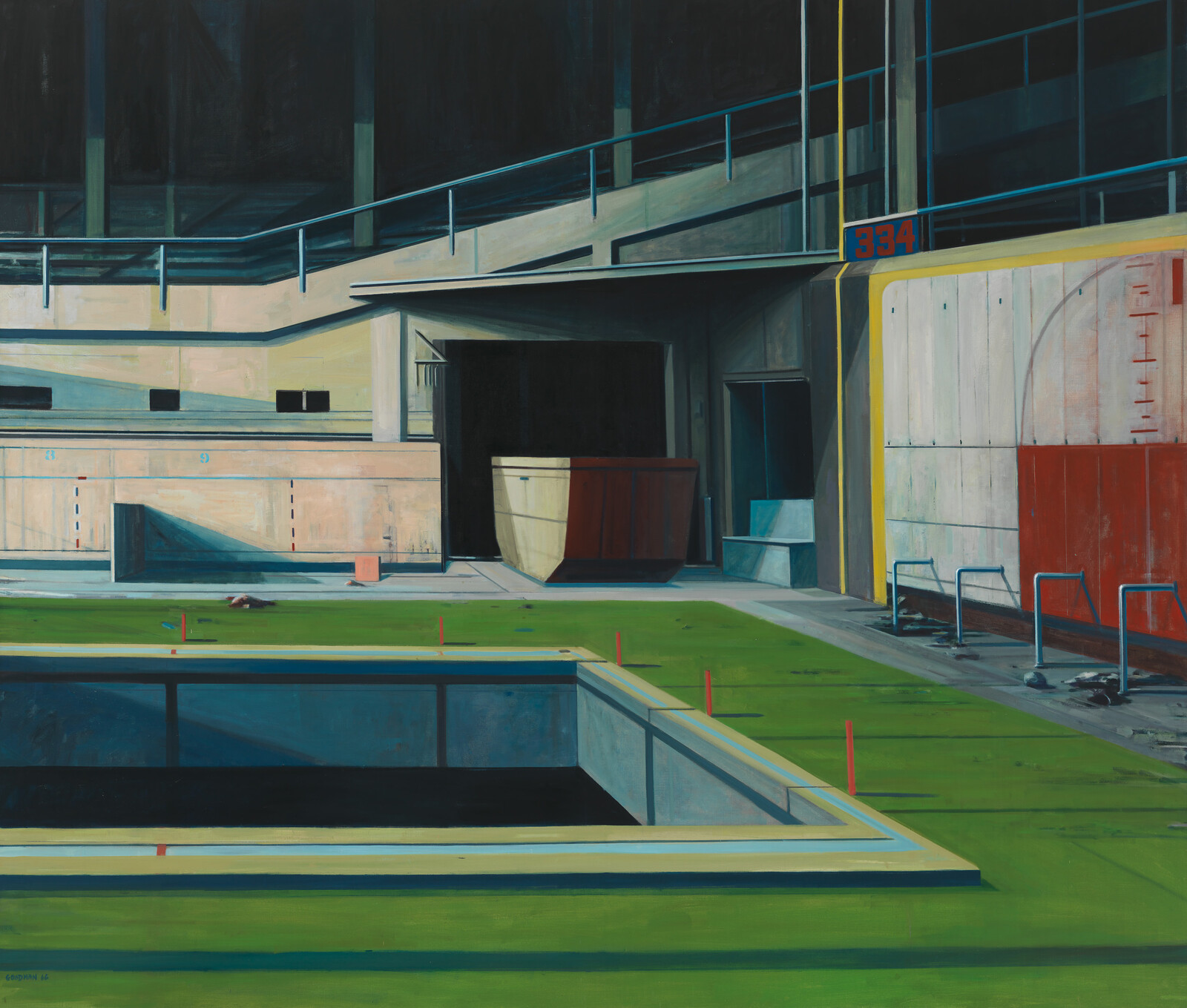 An empty rectangular pool sits on a green floor inside an abandoned, dimly lit sports arena.