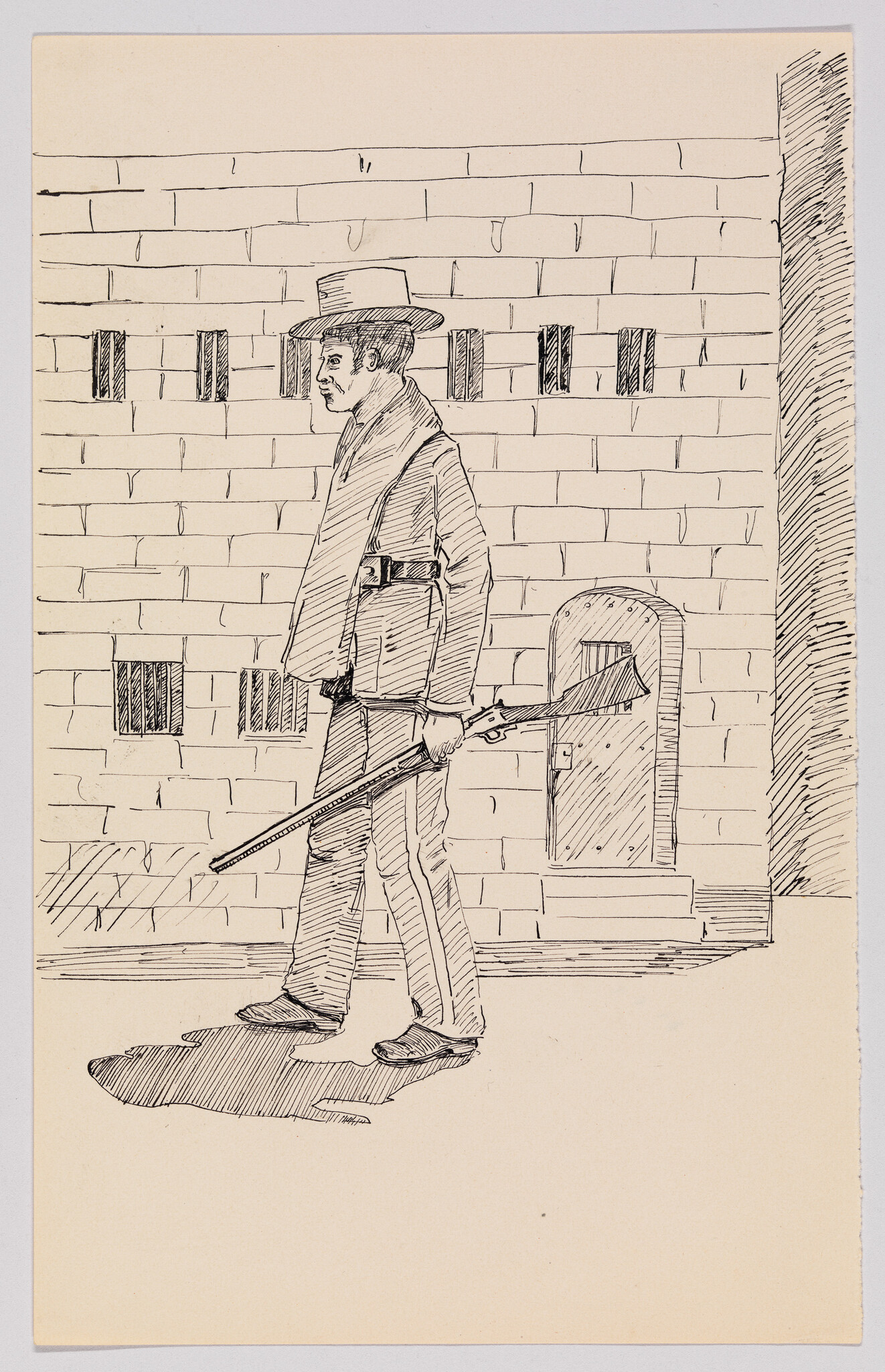 A man in a hat walks beside a brick wall carrying a long rifle.