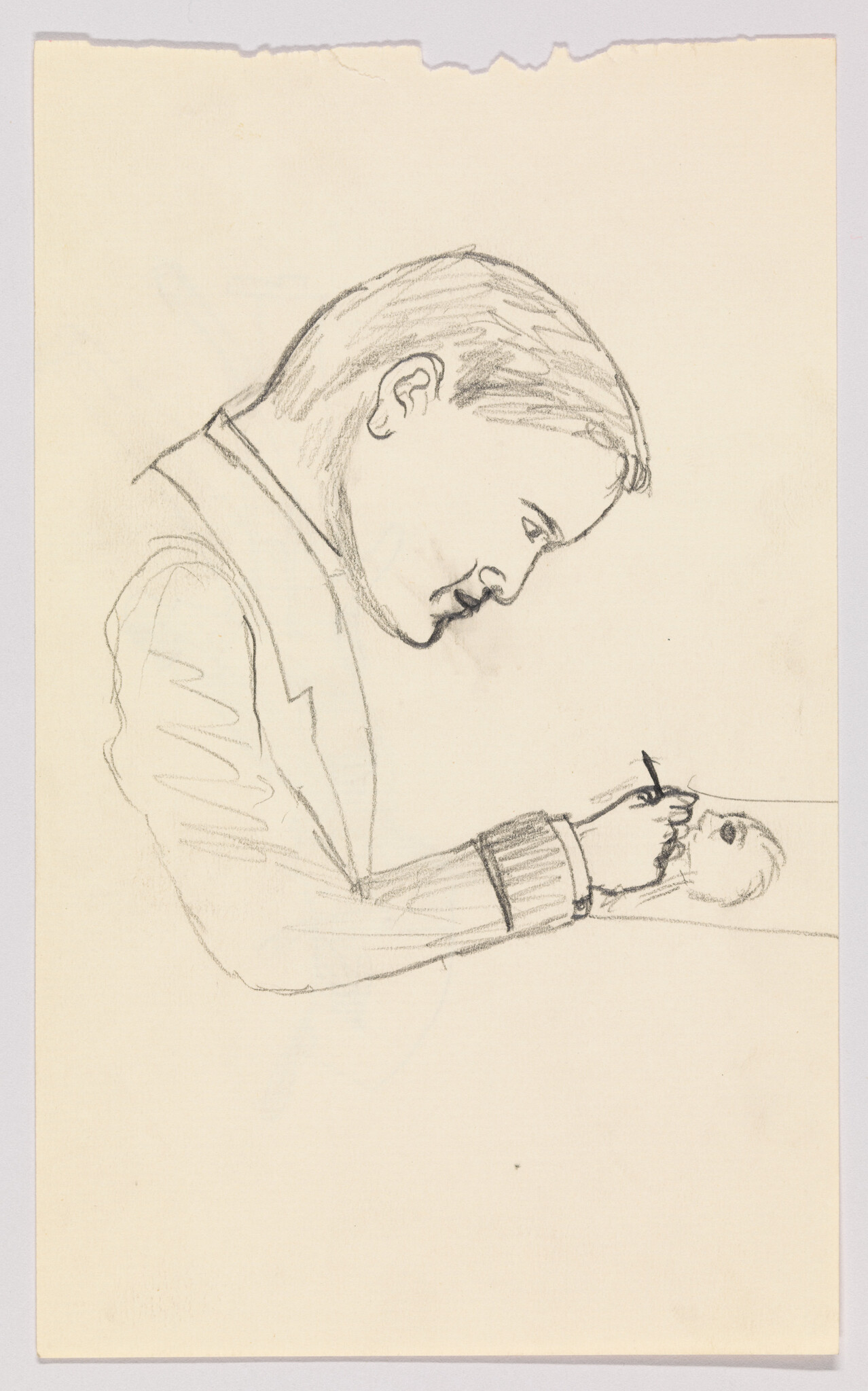 Man leans over a table, concentrating as he sketches a small skull with a pencil.