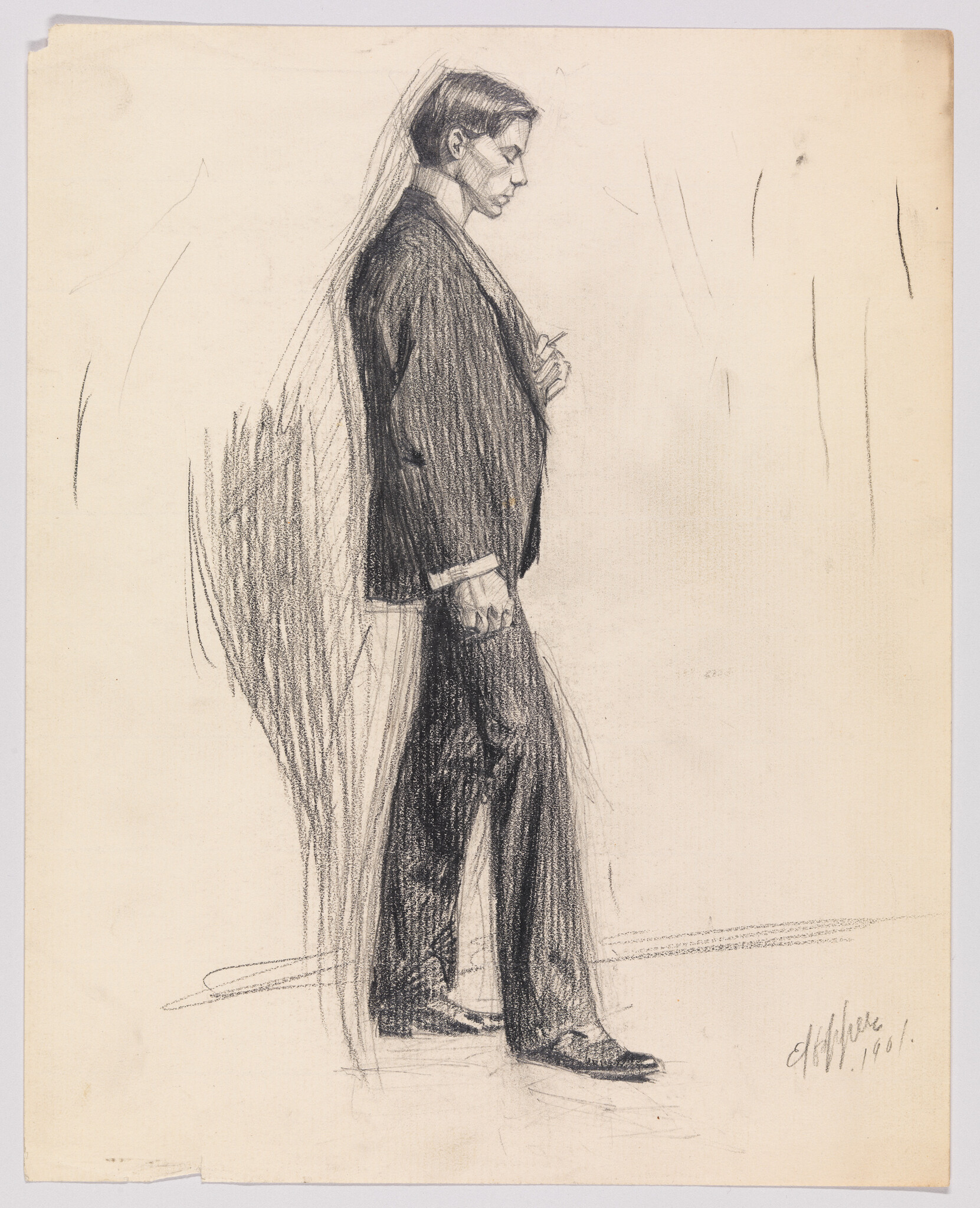 Young man in suit standing in profile with hands clasped at his chest.