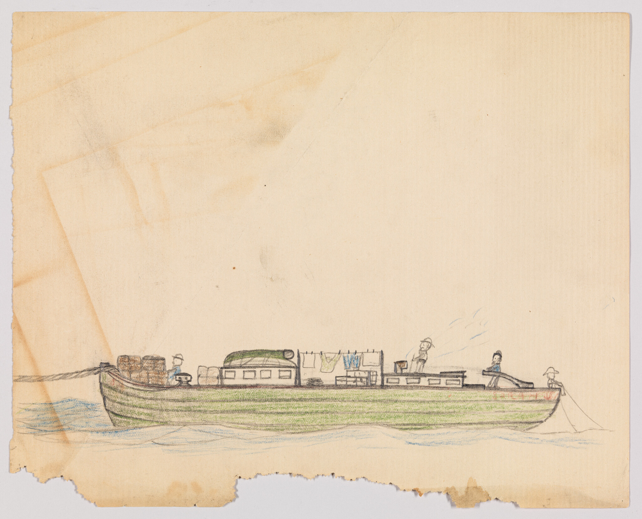 A long green cargo boat on calm water with people working and clothes hanging.