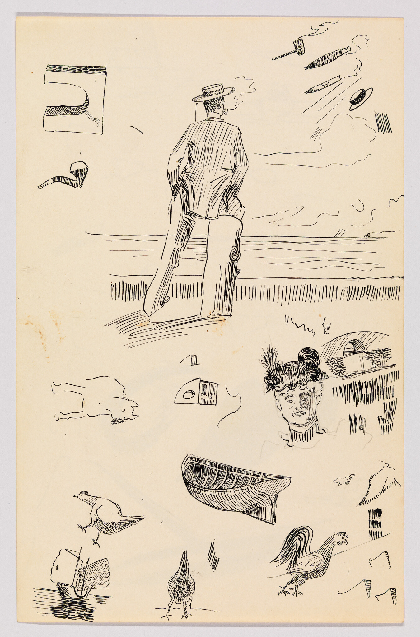 A man in a hat stands on the shore smoking and looking out over the sea.