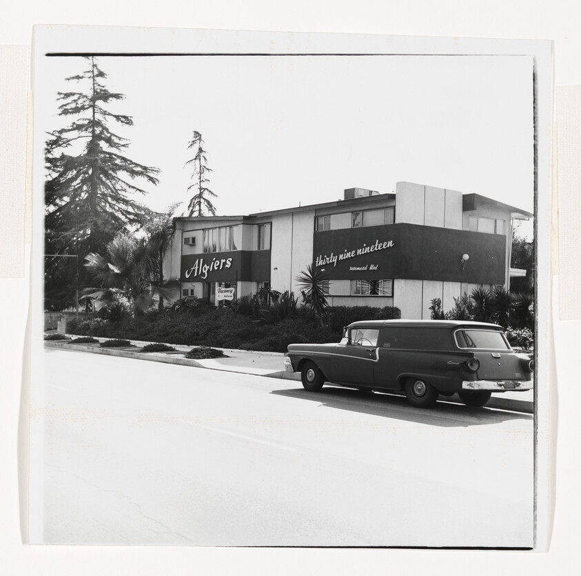 Two-story Algiers motel with 'thirty nine nineteen' sign and a parked vintage station wagon.