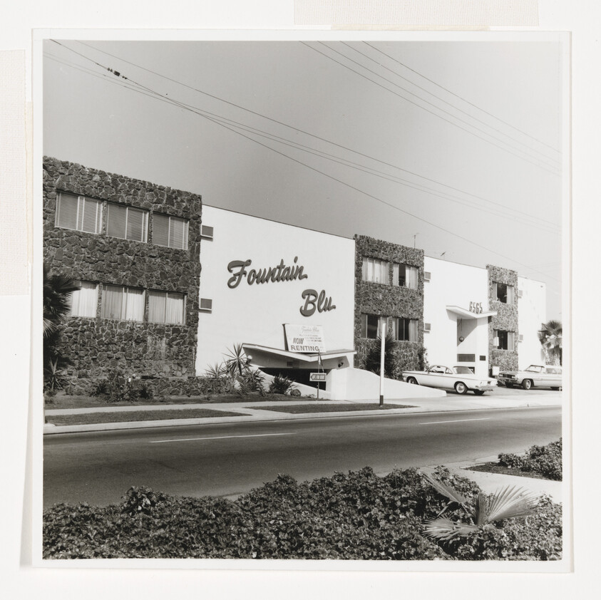 Fountain Blu apartment building with "Now Renting" sign and cars parked along the driveway.