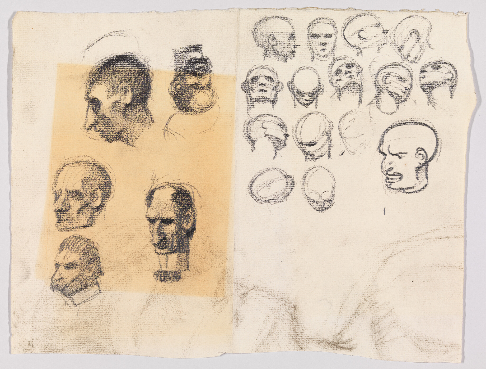 Several charcoal head and skull studies on a two-page sketchbook spread showing varied angles and expressions.