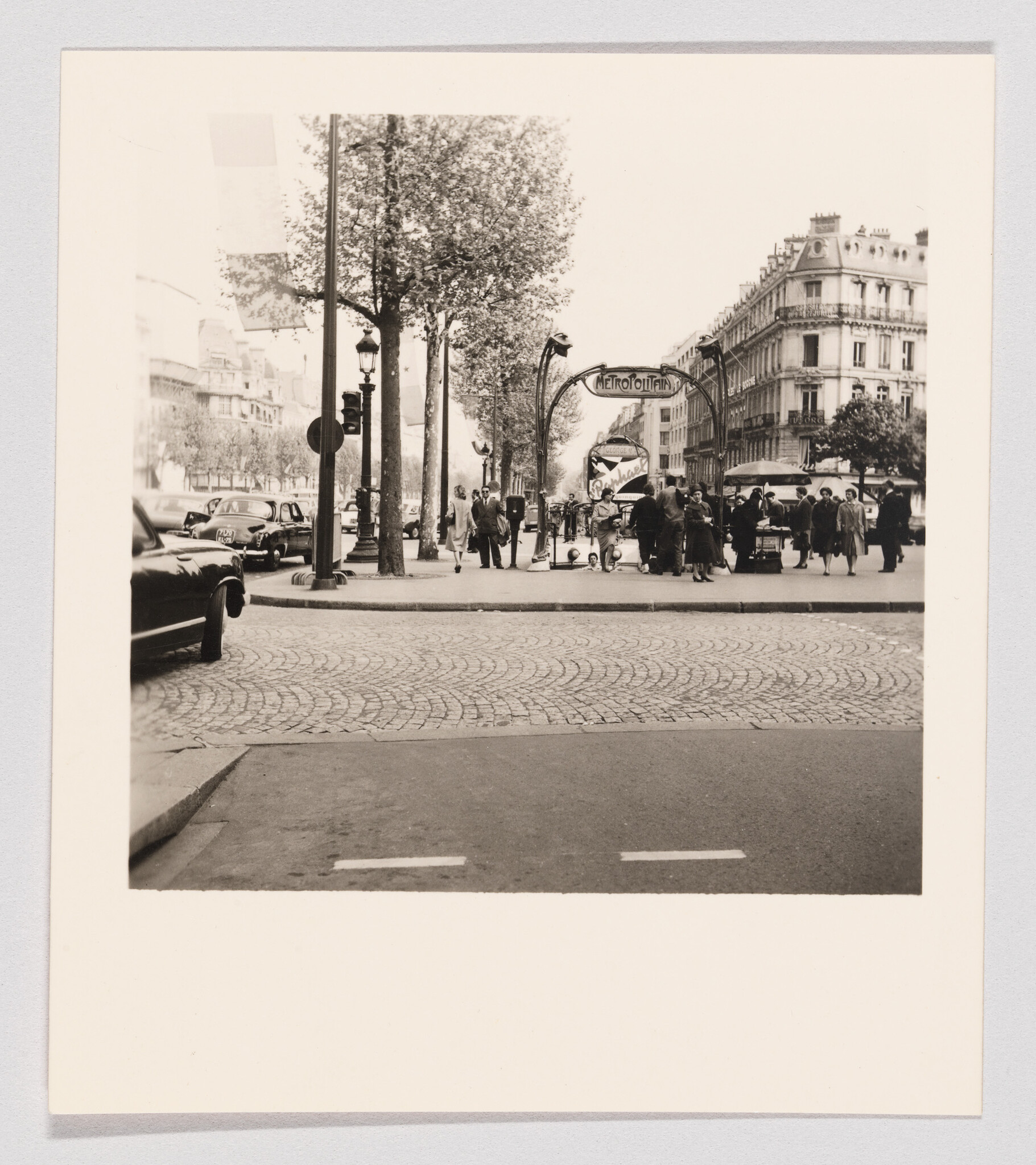 Crowd of people entering and leaving a Paris Métropolitain subway station beneath an ornate sign.