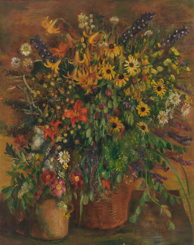 A large basket overflowing with bright wildflowers and greenery beside a small vase.