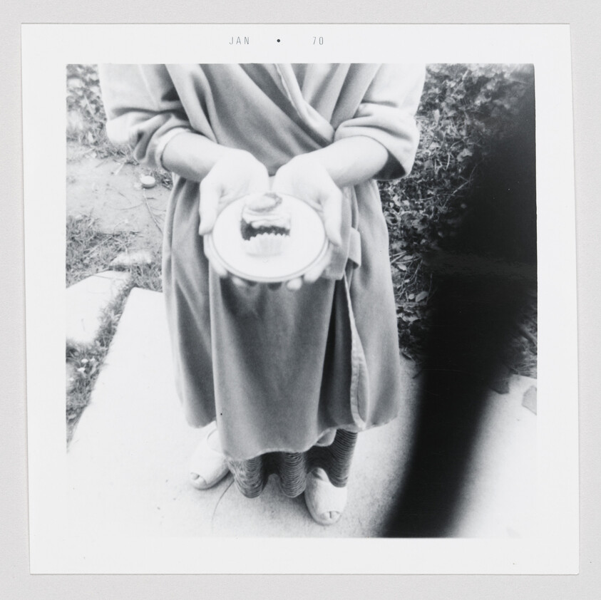 Person in a robe holds a small plate with a set of false teeth toward the camera.