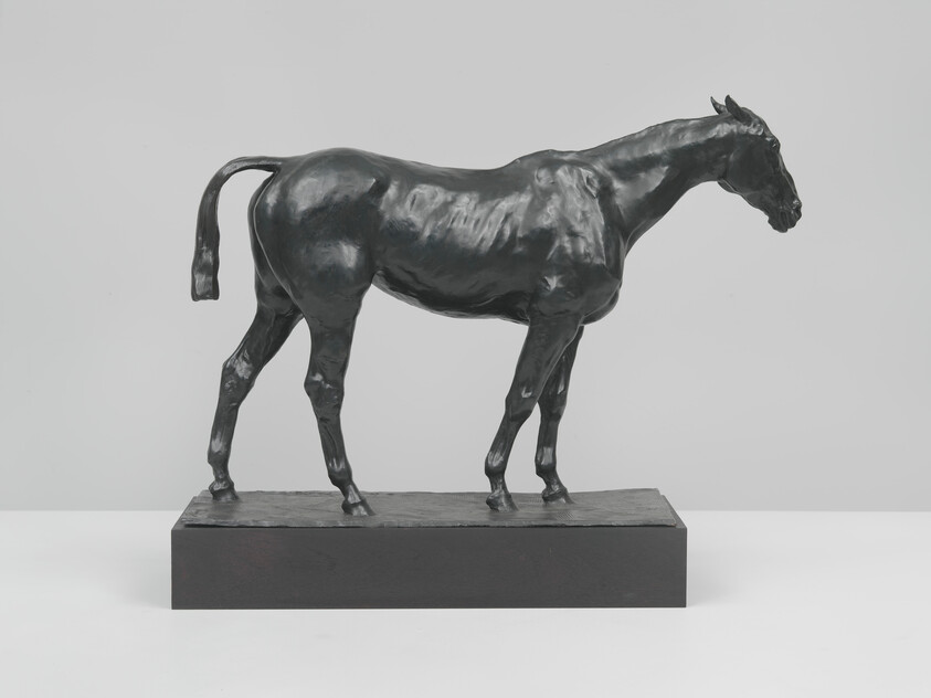 Bronze horse sculpture standing on a rectangular base, facing right with a slightly raised tail.