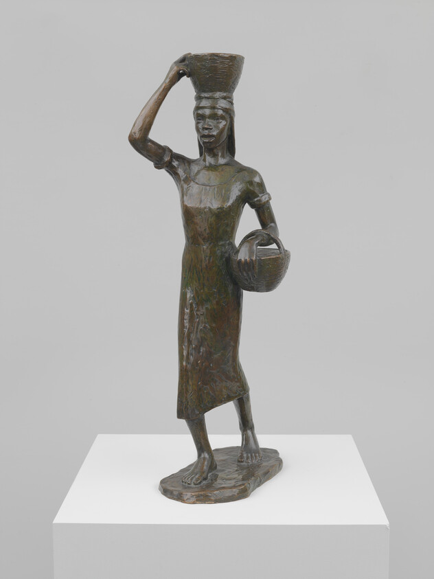 Bronze sculpture of a woman carrying a basket on her head and holding another.