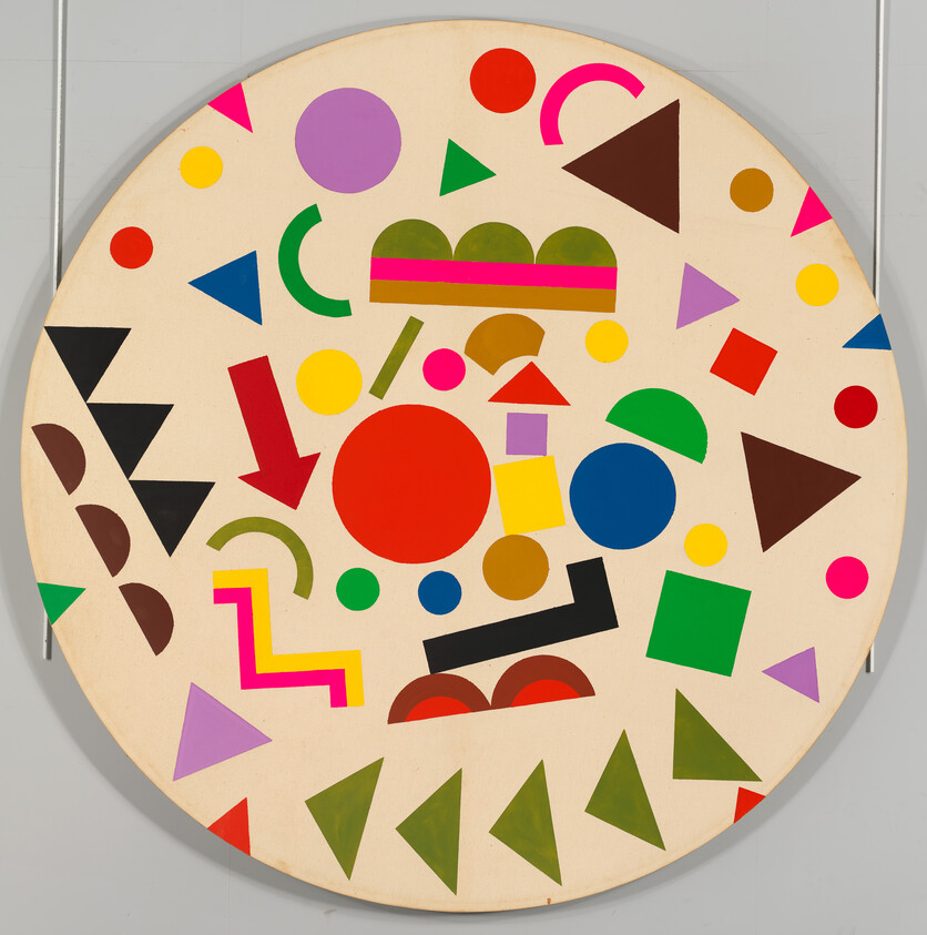 A round beige board covered with scattered colorful geometric shapes like circles, triangles, and squares.