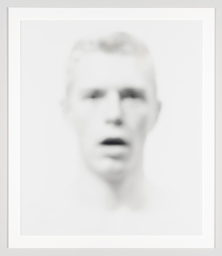 Blurry pale face with open mouth and soft, indistinct features centered on a white background.