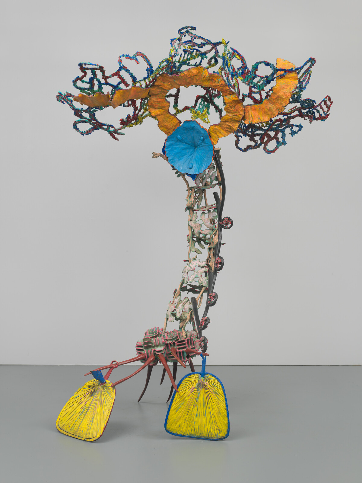 Interior of an art gallery with paintings and sculptures displayed on walls and freestanding panels.